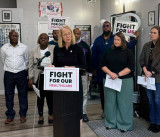 Representative Morrison stands at a podium with Minnesotans behind her