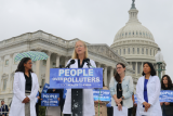 Kelly Morrison stands at press conference in white doctor's coat