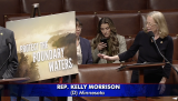 Rep. Morrison points to a poster that says "Protect the Boundary Waters"