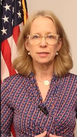 Representative Kelly Morrison stands in front of a U.S. flag