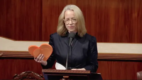 Representative Morrison holds stack of orange letters in the shape of hearts
